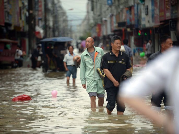 CHINA : This picture taken on October 7, 2013 shows residents making their way through a flooded street in Cangnan county, east China's Zhejiang province. Typhoon Fitow, which barrelled into China's east coast early on October 7 packing winds of more than 200 kilometres (124 miles) an hour, killed at least five people and impacted 4.5 million, state media reported. CHINA OUT AFP PHOTO