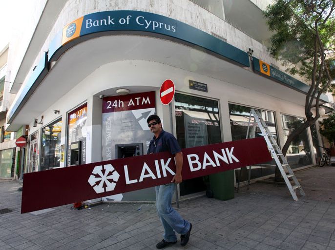 epa03709821 Workmen remove a Laiki Bank sign, replacing it with a Bank of Cyprus one, in the center of Nicosia, Cyprus, 21 May 2013. Some of Laiki Bank's assets are being merged with the Bank of Cyprus. EPA/KATIA CHRISTODOULOU