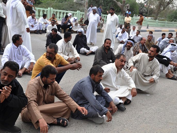 متضررون يجلسون في الشارع الرئيس امام مبنى محافظة البصرة احتجاجا على اهمالهم