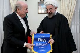A handout picture released by the Iranian presidency shows the Islamic Republic's President Hassan Rouhani (R) receiving a gift from FIFA President Sepp Blatter during a meeting in Tehran on November 6, 2013. Blatter is on region tour. AFP PHOTO / HO / IRANIAN PRESIDENCY