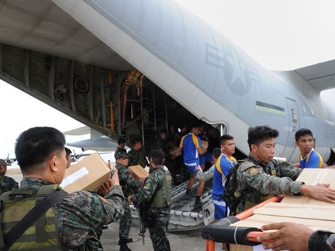 TA1474 - Tacloban, -, PHILIPPINES : Philippine and US military personnel unload relief goods from a US military C-130 plane at Tacloban airport in the central Philippines on November 11, 2013, after Super Typhoon Haiyan devastated the city on November 8. US military planes on November 11 joined a frantic effort to rescue famished survivors of the monster typhoon that may have killed 10,000 people in the Philippines, as local security forces struggled to contain looting. AFP PHOTO / TED ALJIBE