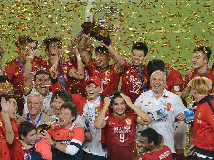 Guangzhou Evergrande celebrate with the trophy and coach Marcello Lippi (bottom L) after winning their AFC League second leg final football game against FC Seoul in Guangzhou on November 9, 2013. The final score was 1:1 giving
