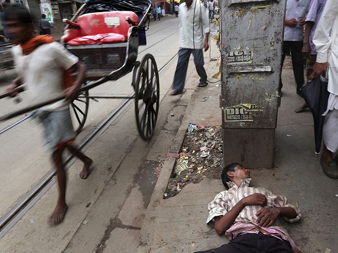 epa03920661 A drunk Indian man (C) lays on a pavement as commuters walk past next to a country liquor shop in Calcutta, Eastern India, 23 October 2013