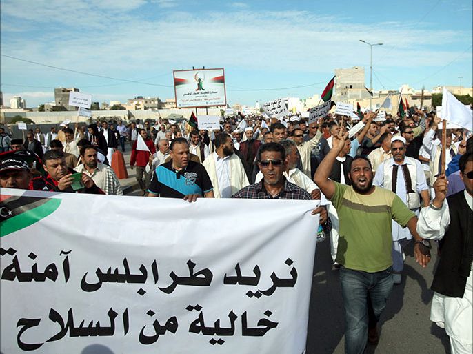 epa03951488 Libyan protesters gather during a demonstration calling on militiamen to vacate their headquarters in southern Tripoli, Libya, 15 November 2013. The sign at (L) reads, in Arabic, 'We want Tripoli to be safe and free of