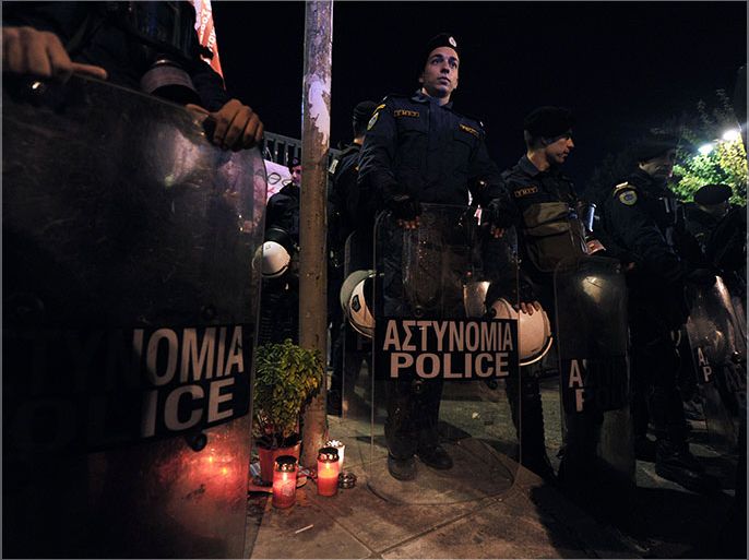 Candles are lit in front of the riot police as people demonstrate outside the former state broadcaster ERT heaquarters in a northern Athens suburb, on November 7, 2013 after the Greek riot police forcibly evacuated it. Greek riot police stormed the headquarters of former public broadcaster ERT in a pre-dawn raid on November 7, forcibly removing employees who had been occupying the site since its shock shutdown five months ago. The raid triggered protests outside the headquarters of almost 3,000 people, at the urging of unions and leftwing political parties. AFP PHOTO / LOUISA GOULIAMAKI