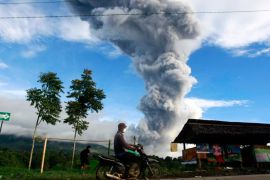 A resident rides his motorcycles as mount Sinabung spews smoke and ashes, at Tiga Serangkai village in Karo, North Sumatra, Indonesia, 24 November 2013. According to the National Disaster Management Agency (BNPB), more than 6,000 people have fled their homes in Indonesia's North Sumatra province after a series of volcanic eruptions. The Mount Sinabung volcano in Karo district has erupted intermittently since September. EPA/DEDI SAHPUTRA