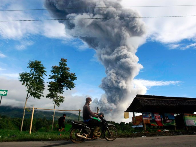 A resident rides his motorcycles as mount Sinabung spews smoke and ashes, at Tiga Serangkai village in Karo, North Sumatra, Indonesia, 24 November 2013. According to the National Disaster Management Agency (BNPB), more than 6,000 people have fled their homes in Indonesia's North Sumatra province after a series of volcanic eruptions. The Mount Sinabung volcano in Karo district has erupted intermittently since September. EPA/DEDI SAHPUTRA