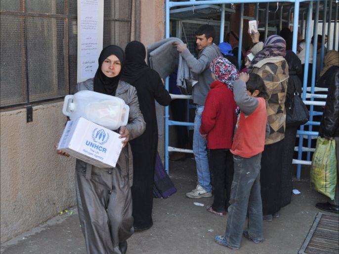 A handout picture released by the United Nation's Refugee Agency (UNHCR) on December 29, 2013, shows Syrian families collecting emergency relief items being distributed to some of the thousand of displaced families in Qamishly, northeastern Syria, as air lifted relief aid to long-isolated regions winds down. The last UNHCR cargo flight landed at Qamishly airport carrying assistance urgently needed by displaced the persons. UNHCR commenced its airlift on December 17, with 12 special cargo flights totaling nearly 300 metric tons of relief aid to help more than 50,000 people in north-eastern Syria cope with winter. AFP PHOTO/HO/UNHCR