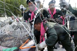 angkok, -, THAILAND : TOPSHOTSThai policemen cut a barbed wire fence to open barricades at the Metrpolitan police headquarters in Bangkok on December 3, 2013. Hundreds of Thai opposition protesters entered the government headquarters unopposed on December 3, after police said they would offer no resistance to the demonstrators who have vowed to topple Prime Minister Yingluck Shinawatra. AFP PHOTO/Indranil MUKHERJEE