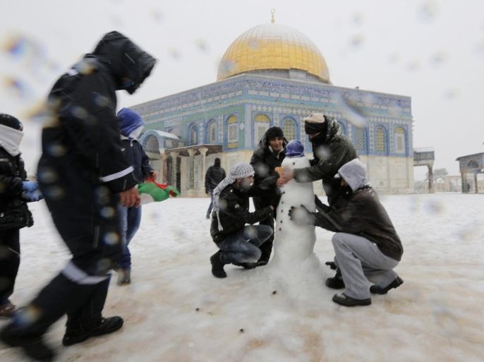 People build a snowman in front of the Dome of the Rock in the compound known to Muslims as Noble Sanctuary and to Jews as Temple Mount, in Jerusalem's Old City December 12, 2013. Snow fell in Jerusalem and parts of the occupied West Bank where schools and offices were widely closed and public transport was paused. REUTERS/Ammar Awad (JERUSALEM - Tags: RELIGION ENVIRONMENT)