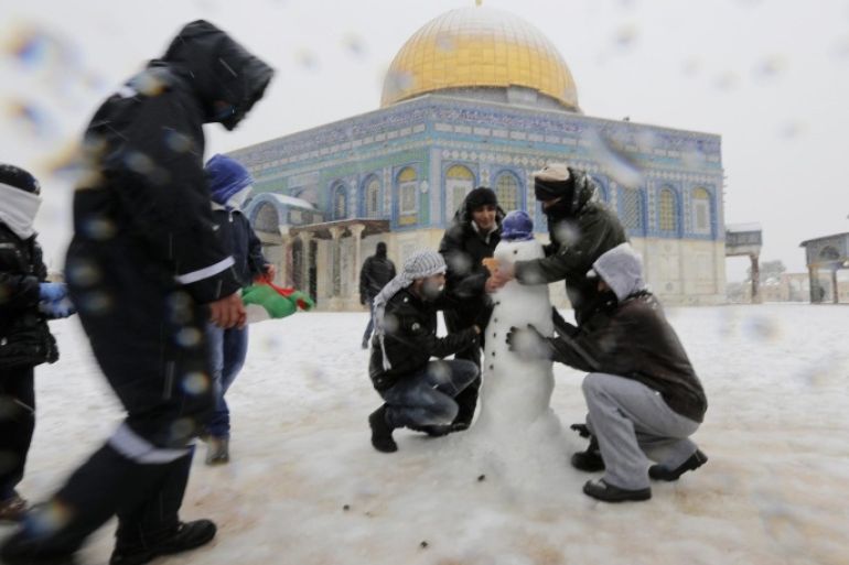 People build a snowman in front of the Dome of the Rock in the compound known to Muslims as Noble Sanctuary and to Jews as Temple Mount, in Jerusalem's Old City December 12, 2013. Snow fell in Jerusalem and parts of the occupied West Bank where schools and offices were widely closed and public transport was paused. REUTERS/Ammar Awad (JERUSALEM - Tags: RELIGION ENVIRONMENT)