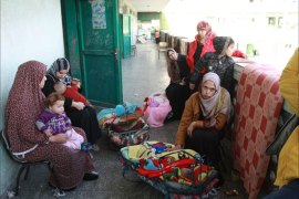 زوجة وطفل اللاجئ حسن أبو زرد ومعها عدد من زوجات واطفال أشقائه في على مقربة من حجرة أحد