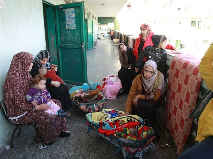 زوجة وطفل اللاجئ حسن أبو زرد ومعها عدد من زوجات واطفال أشقائه في على مقربة من حجرة أحد