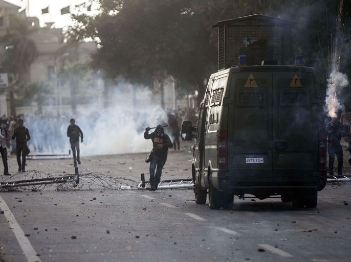 Egyptian students who support the Muslim Brotherhood (background) clash with riot policemen (foreground) outside the University of Cairo campus in the capital on December 11, 2013. AFP PHOTO / MAHMOUD KHALED