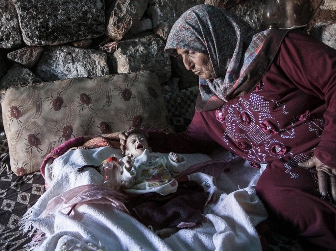 In this Friday, Sept. 27, 2013 photo, a displaced Syrian woman comforts her one-month old grandchild Fatima inside a stone house near Kafer Rouma, in ancient ruins used as temporary shelter by those families who have fled from the heavy fighting and shelling in the Idlib province countryside of Syria. Fatima was born just a month ago amid the ancient ruins outside Kafer Rouma, a village in northern Syria that has come under shelling by President Bashar Assad s forces during the country s civil war. Her family fled their home in the village to the giant stone blocks and centuries-old walls so that Fatima s mother could give birth in relative safety.