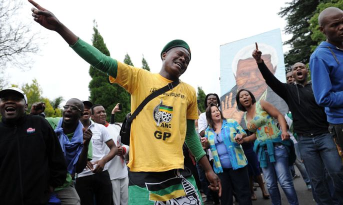 AFRICA : A man wearing a yellow t-shirt of the South African ANC ruling party grieves with other people on December 6, 2013 outside the house of former South African President Nelson Mandela in Johannesburg. Mandela, the revered icon of the anti-apartheid struggle in South Africa and one of the towering political figures of the 20th century, has died aged 95. Mandela, who was elected South Africa's first black president after spending nearly three decades in prison, had been receiving treatment for a lung infection at his Johannesburg home since September, after three months in hospital in a critical state. AFP PHOTO / STEPHANE