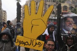 Supporters of the Muslim Brotherhood and ousted Egyptian President Mohamed Mursi, raise a placard with a "Rabaa" sign that reads "Symbol of steadfastness" during a protest in Al-Haram street, in Cairo December 13, 2013. The "Rabaa" sign is in reference to the police clearing of the Rabaa al-Adawiya protest camp on August 14. REUTERS/Stringer (EGYPT - Tags: POLITICS CIVIL UNREST)