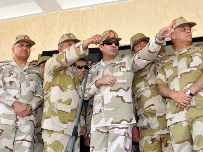 A handout picture released by the Egyptian Ministry of Defence shows Egypt's military chief Abdel Fattah al-Sisi (C) gesturing as he stands alongside army officers during the graduation ceremony of a new batch of non-commissioned officers, in Cairo, on December 26, 2013. The military-installed government's listing of Egypt's Muslim Brotherhood as a terrorist group signals determination to uproot its vast grass-roots network, possibly radicalising the Islamists as they go underground, analysts said. AFP PHOTO/EGYPTIAN MINISTER OF DEFENCE/HO == RESTRICTED TO EDITORIAL USE - MANDATORY CREDIT "AFP PHOTO / EGYPTIAN MINISTER OF DEFENCE" - NO MARKETING NO ADVERTISING CAMPAIGNS - DISTRIBUTED AS A SERVICE TO CLIENTS ==