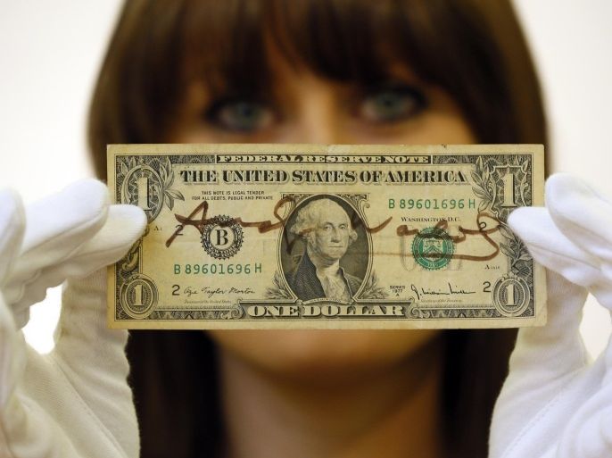 Christie's specialist Caitlin Graham poses for photographers with a dollar bill signed by Andy Warhol, during a photocall at the auction rooms in London, Friday, Nov. 23, 2012. The dollar estimated at 1,000- 1,500 pounds (1,600- 2,400 US Dollars) will go on sale in the Pop Culture auction on Nov. 29 in London.