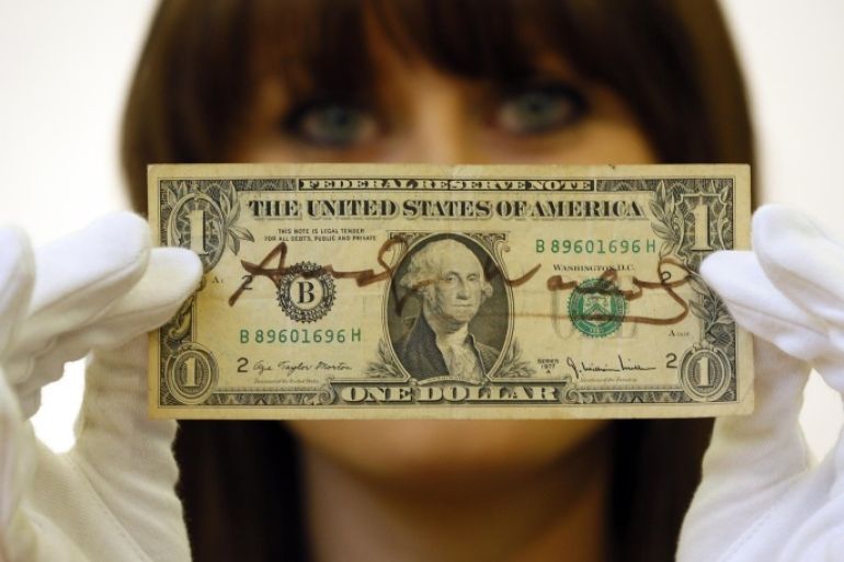 Christie's specialist Caitlin Graham poses for photographers with a dollar bill signed by Andy Warhol, during a photocall at the auction rooms in London, Friday, Nov. 23, 2012. The dollar estimated at 1,000- 1,500 pounds (1,600- 2,400 US Dollars) will go on sale in the Pop Culture auction on Nov. 29 in London.