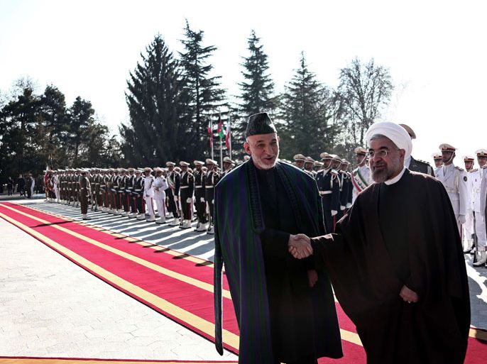 BEH190 - Tehran, -, IRAN : Iranian President Hassan Rouhani (R) shakes hands with Afghan President Hamid Karzai (C) during a welcoming ceremony at Tehran's Saadabad Palace on December 8, 2013.Karzai arrived in Iran for talks amid disagreement with the United States over a security accord that would allow some NATO forces to stay in Afghanistan. AFP PHOTO/BEHROUZ MEHRI