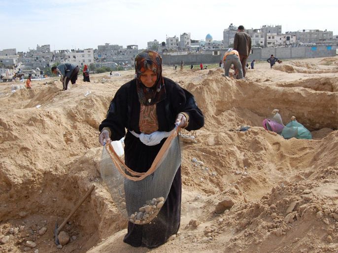 مسنة تنقب عن الحصى الذي يستخدم في البناء و يمنع الاحتلال مروره إلى غزة