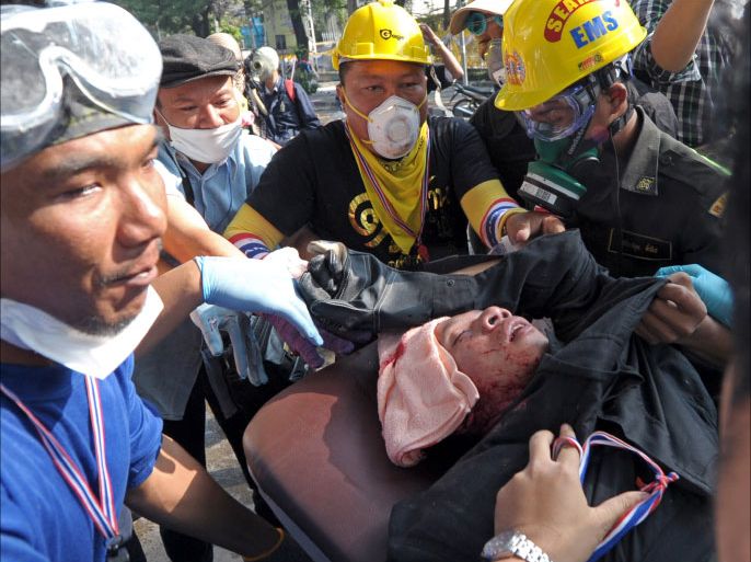 TOPSHOTSThai anti government protesters carry an injured from gunshot during a rally at a stadium to register party-list candidates in Bangkok on December 26, 2013. Thai police fired tear gas as violent