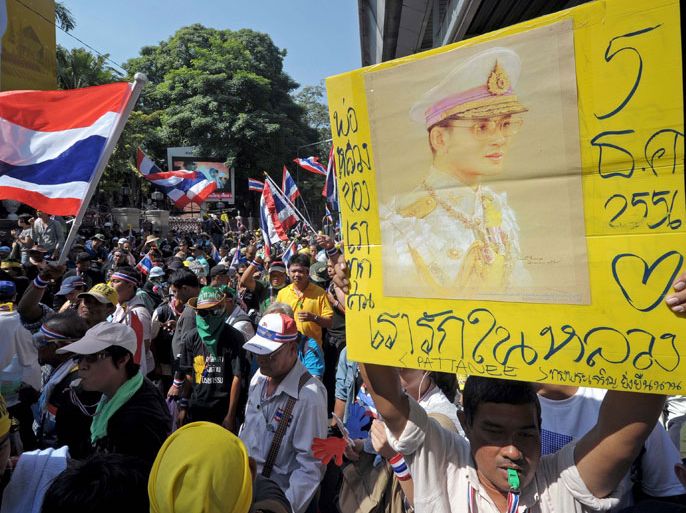 Thai anti government protesters hold a portrait of King Bhumibol Adulyadej as they rally at in front the national police headquarters in Bangkok on December 4, 2013. Thailand's anti-government protesters and security forces observed a temporary truce as the nation prepared to mark the birthday of the revered king, after police stepped back in a dramatic move to calm violent clashes. AFP PHOTO / PORNCHAI KITTIWONGSAKUL