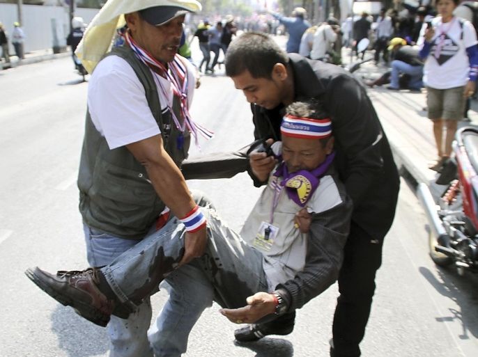 An injured anti-government protester is helped by his fellow protesters after he was hit by a bomb blast during the march with leader Suthep Thaugsuban in downtown Bangkok, Thailand Friday, Jan. 17, 2014. Dozens of people were wounded in Thailand's capital Friday when an explosion hit anti-government demonstrators marching through Bangkok in some of the bloodiest violence reported this year. (AP Photo/Daily News) THAILAND OUT