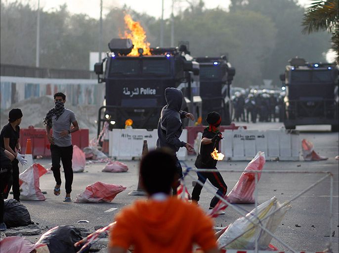 Anti-government protesters throw a Molotov cocktail and stone at riot-police armored personnel carriers during clashes after the funeral procession of Fadhel Abas Muslim in the village of Diraz, west of Manama, January 26, 2014. The Ministry of Interior issued a statement that Muslim was injured when a police officer tried to arrest him as he was wanted in connection with a December 28 case involving substantial amount of weapons and high-grade explosives smuggled into Bahrain via boat. Muslim was shot in self-defense as he tried to hit the police officer and escape in the officer's car, the statement added. Muslim was under treatment since January 8, 2014 and died on January 26, 2014 from the bullet wound at the back of his skull. REUTERS/Hamad I Mohammed (BAHRAIN - Tags: POLITICS CRIME LAW CIVIL UNREST)