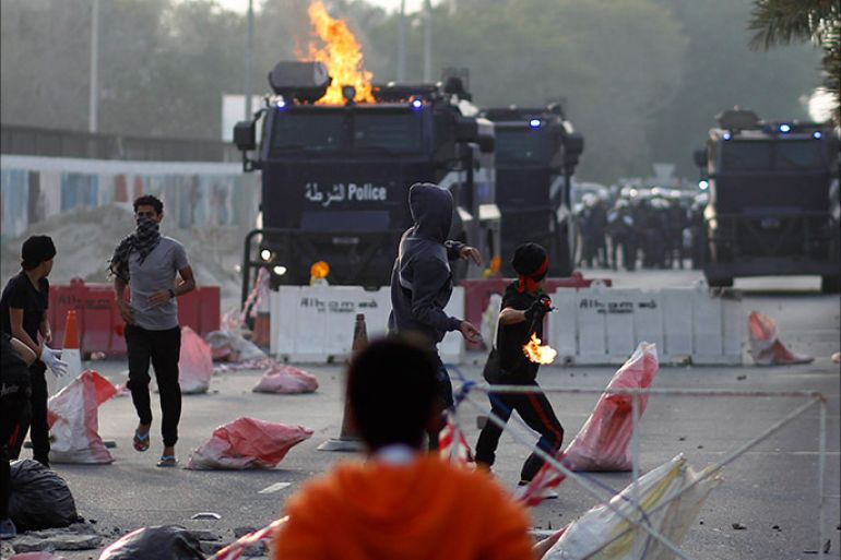 Anti-government protesters throw a Molotov cocktail and stone at riot-police armored personnel carriers during clashes after the funeral procession of Fadhel Abas Muslim in the village of Diraz, west of Manama, January 26, 2014. The Ministry of Interior issued a statement that Muslim was injured when a police officer tried to arrest him as he was wanted in connection with a December 28 case involving substantial amount of weapons and high-grade explosives smuggled into Bahrain via boat. Muslim was shot in self-defense as he tried to hit the police officer and escape in the officer's car, the statement added. Muslim was under treatment since January 8, 2014 and died on January 26, 2014 from the bullet wound at the back of his skull. REUTERS/Hamad I Mohammed (BAHRAIN - Tags: POLITICS CRIME LAW CIVIL UNREST)