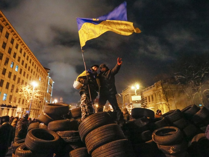 Protesters hold a National flag on a barricade as they have a temporary truce with riot police during an anti-government protest in downtown Kiev, Ukraine, 23 January 2014. At least two people died of gunshot wounds on 22 January during anti-government protests in Ukraine, prosecutors said. A demonstrator also reportedly fell to his death after being chased by police. The violent protests have been raging in the Ukrainian capital since 19 January.