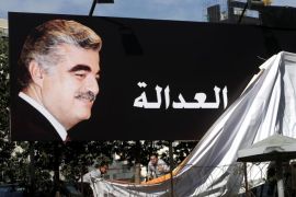 Supporters of slain former Lebanese Prime Minister Rafik Hariri, uncover a giant billboard with his portrait and Arabic that reads, "Justice," a few hundred of meters (yards) from the site of the 2005 blast, in Beirut, Lebanon, Thursday, Jan. 16, 2014. Nearly nine years after a truck bomb killed Hariri and 22 others, the trial started Thursday for four Hezbollah suspects accused of plotting the sectarian assassination. (AP Photo/Hussein Malla)