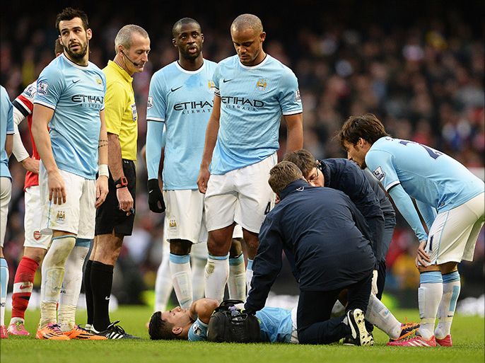 epa03990390 Arsenal's Sergio Aguero (bottom)receives medical assistance before leaving the pitch due to an injury during the English Premier League soccer match between Manchester City FC and Arsenal FC in Manchester, Britain, 14 December 2013