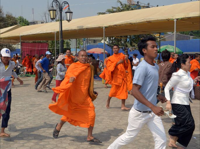 Cambodian Buddhist monks and protesters run at the Democracy Park as security personnel armed with shields and batons flooded into the area in Phnom Penh on January 4, 2014. Cambodian authorities on January 4, dispersed opposition protesters from their rally base in the capital and halted further protests against the kingdom's strongman premier, a day after police launched a deadly crackdown on striking garment workers. AFP PHOTO/ TANG CHHIN SOTHY