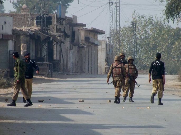 Pakistani police and army soldiers stand guard on a road leading to the site of bomb explosion in Bannu, Pakistan on Sunday Jan. 19, 2014. A regular Sunday morning troop rotation going into the Pakistani tribal region of North Waziristan was shattered by an explosion that killed tens of people, mostly paramilitary troops. The Pakistani Taliban claims responsibility for placing the bomb on one of the trucks hired for the job. (AP Photo/Ijaz Muhammad)