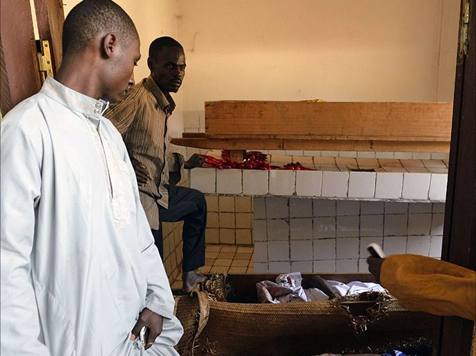 Two men show the bodies of civilians lying in a mortuary after they were killed in the PK12 district of Bangui on January 16, 2014. At least seven people were killed in overnight violence in Bangui, according to a compiled toll from the Red Cross and AFP. Tensions remain high in the city, where French forces are patrolling in a bid to quell unrest that continues to simmer between Muslim ex-rebels and the Christian majority. AFP PHOTO / ERIC FEFERBERG