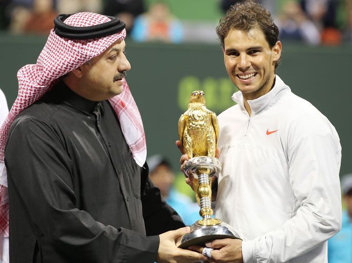 epa04008280 Spain's Rafael Nadal (R) receives his trophy from Qatari Foreign Minister Dr. Khalid bin Mohammed Al-Attiyah (L) after winning the final match against Gael Monfils of France at the ExxonMobil Qatar ATP Open Tennis