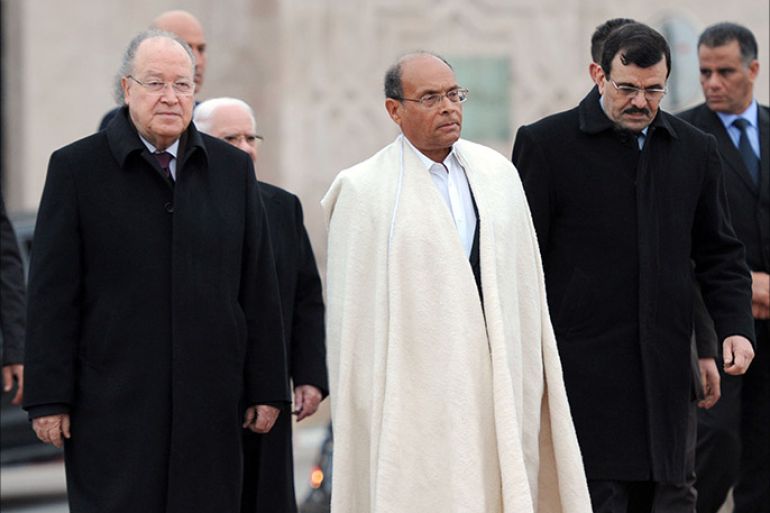 Tunisian President Moncef Marzouki (C), Tunisian Parliament Speaker Mustapha Ben Jaafar (L) and outgoing Prime Minister Ali Larayedh (R) review troops during an official ceremony marking the festivities the 3rd anniversary of the uprising
