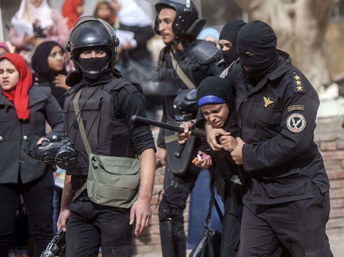 An Egyptian riot policeman detains a female student of al-Azhar University during a protest by students who support the Muslim Brotherhood inside their campus in Cairo on December 30, 2013. Egypt urged Arab League members to enforce a counter terrorism treaty that would block funding and support for the Muslim Brotherhood after Cairo designated it as "terrorist" group. AFP