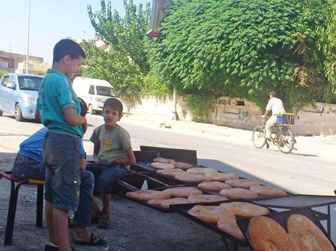 الطفل محمد وهو يبيع ربطا الخبز وبعض المعجنات ليعيل بعائلته - الجزيرة نت