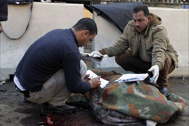 Egyptian forensics inspect a body at the site of a car bomb explosion outside the Cairo police headquarters in the Egyptian capital on January 24, 2014. A bomb near a Cairo metro station was set off, hours after a blast struck police headquarters in the Egyptian capital, killing several people, the health ministry said. AFP PHOTO/KHALED KAMAL