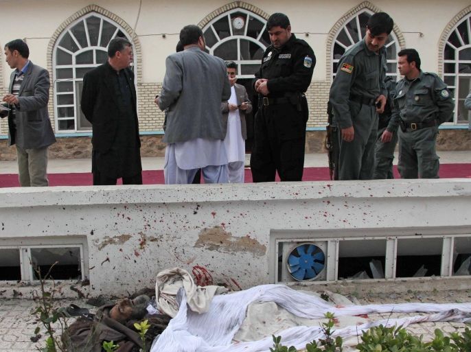 Afghan police look at a dead body of a suicide attacker in a mosque in Herat, Afghanistan, Tuesday, Jan. 14, 2014. An influential former Afghan warlord who served as water and energy minister in a previous administration narrowly escaped an assassination attempt by the suicide attack Friday in the country’s western Herat province, a police spokesman said. (AP Photo/Hoshang Hashimi)