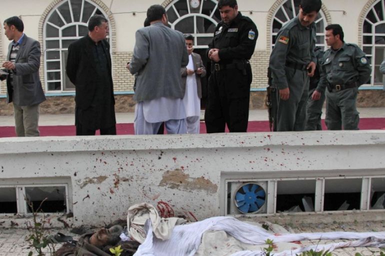 Afghan police look at a dead body of a suicide attacker in a mosque in Herat, Afghanistan, Tuesday, Jan. 14, 2014. An influential former Afghan warlord who served as water and energy minister in a previous administration narrowly escaped an assassination attempt by the suicide attack Friday in the country’s western Herat province, a police spokesman said. (AP Photo/Hoshang Hashimi)