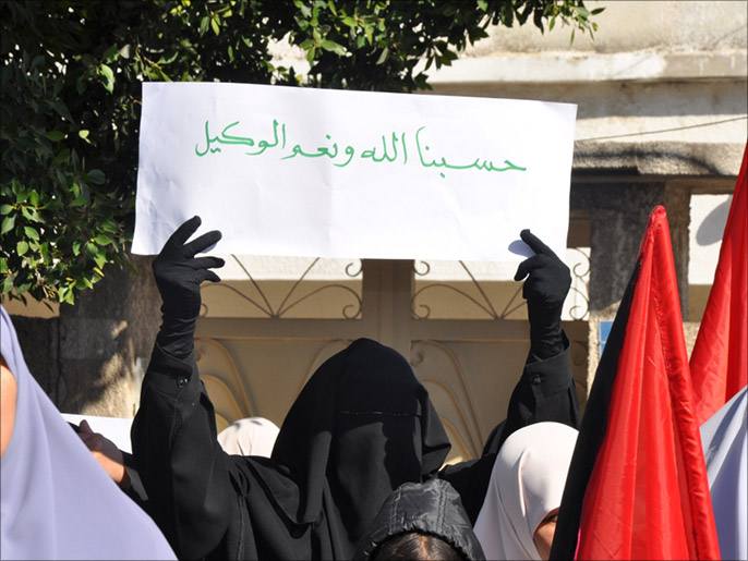 امرأة تحمل لافتة تعبر عن قنوطها من مواقف العرب (الجزيرة)