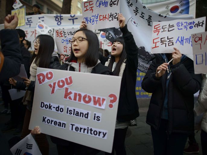 081 - SEOUL, -, REPUBLIC OF KOREA : Demonstrators hold placards and shout slogans during a protest over the disputed Dokdo islands in front of the Japanese Embassy in Seoul on February 22, 2014. Japan is holding its annual 'Takeshima Day' commemorating the Takeshima Islands, currently controlled by South Korea which refers to them as the 'Dokdo' islands. AFP PHOTO / Ed Jones