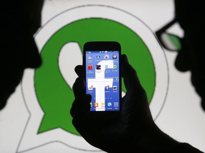An illustration photo shows a man holding a smart phone with a Facebook logo as its screen wallpaper in front of a WhatsApp messenger logo, in Zenica February 20, 2014. REUTERS/Dado Ruvic