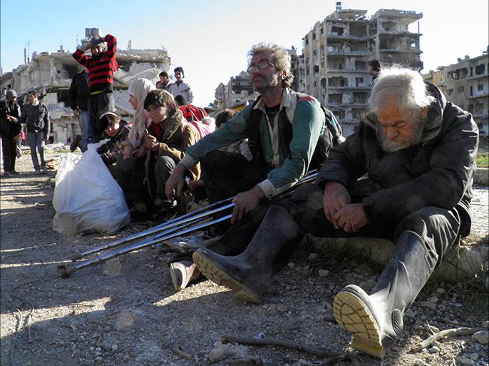 Civilians sit with their belongings as they wait to be evacuated from a besieged area of Homs February 12, 2014. A humanitarian ceasefire allowing the delivery of aid and evacuation of civilians from the Syrian city of Homs could be extended further if there are more people wishing to leave its besieged Old City, the city's governor told Reuters. REUTERS/Thaer Al Khalidiya (SYRIA - Tags: POLITICS CIVIL UNREST CONFLICT)
