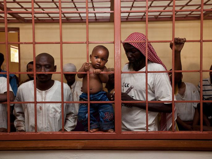 A man suspected of being member of Somalia's Al-Qaeda linked Shebab insurgents holds his baby as he sits with others before their trial at the Shanzu Law courts in the Shimo La Tewa prison in Mombasa on February 3, 2014. Over 100 people arrested after deadly rioting following a police raid on a Kenyan mosque were charged on February 3, 2014 for being members of the Shebab insurgents. "We received information that there was a jihad convention in the mosque and that's when we moved in," said local police chief Robert Kitur. The men in the mosque then "turned violent and attacked our officers". Judge James Ombura ordered the 129 men be held in prison until Friday to allow prosecutors to finish their investigations, when the accused are expected to enter a plea. AFP PHOTO/IVAN LIEMAN