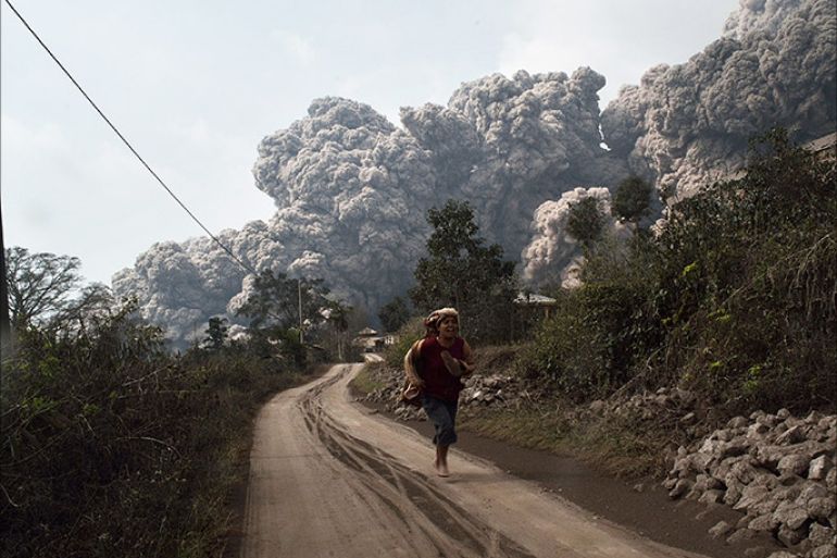 A resident runs away to escape from hot volcanic ash clouds engulfing villages in Karo district during the eruption of Mount Sinabung volcano located in Indonesia's Sumatra island on February 1, 2014. Fourteen people, including four schoolchildren, were killed February 1 after they were engulfed by scorching ash clouds spat out by Indonesia's Mount Sinabung in its biggest eruption in recent days, officials said. AFP PHOTO / SUTANTA ADITYA